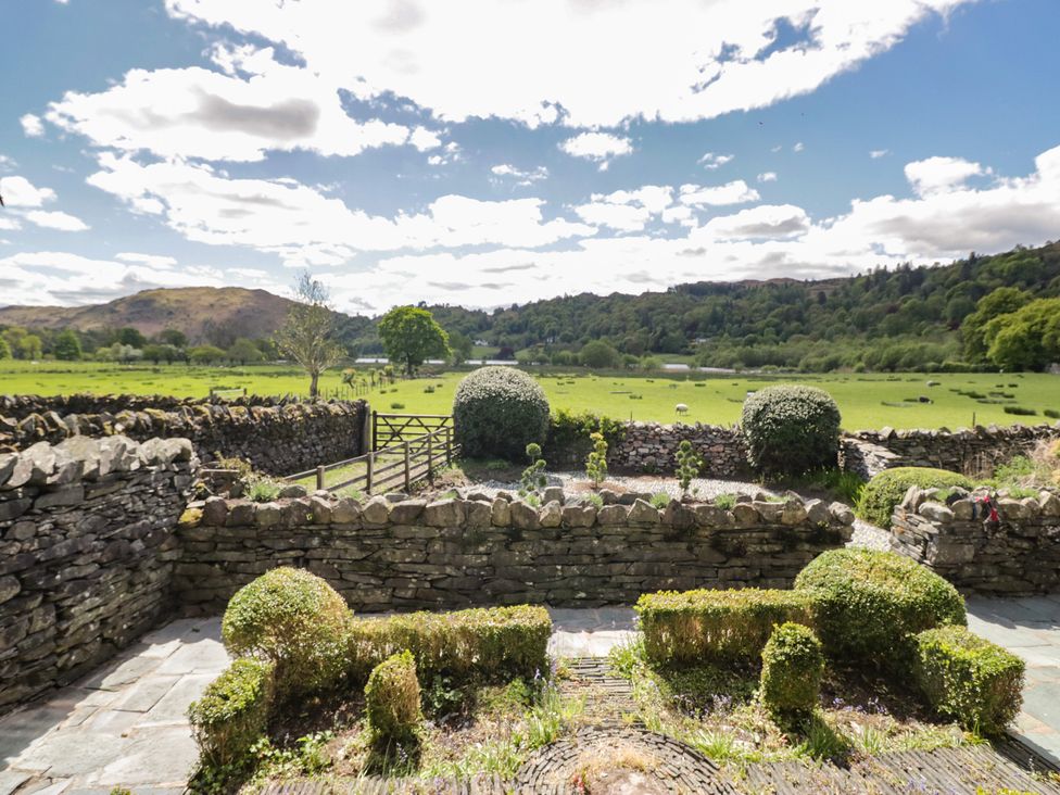 A garden with a stone wall and gate overlooking fields at The Barn at Grasmere in Grasmere