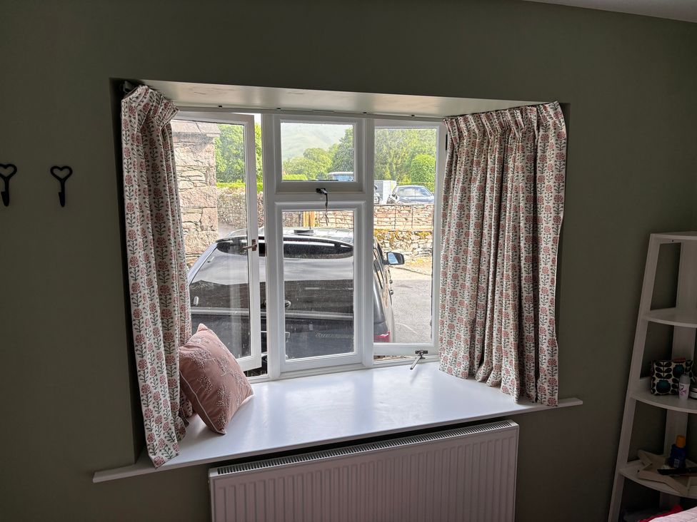 A window with curtains and a pillow on the sill at The Barn at Grasmere in Grasmere