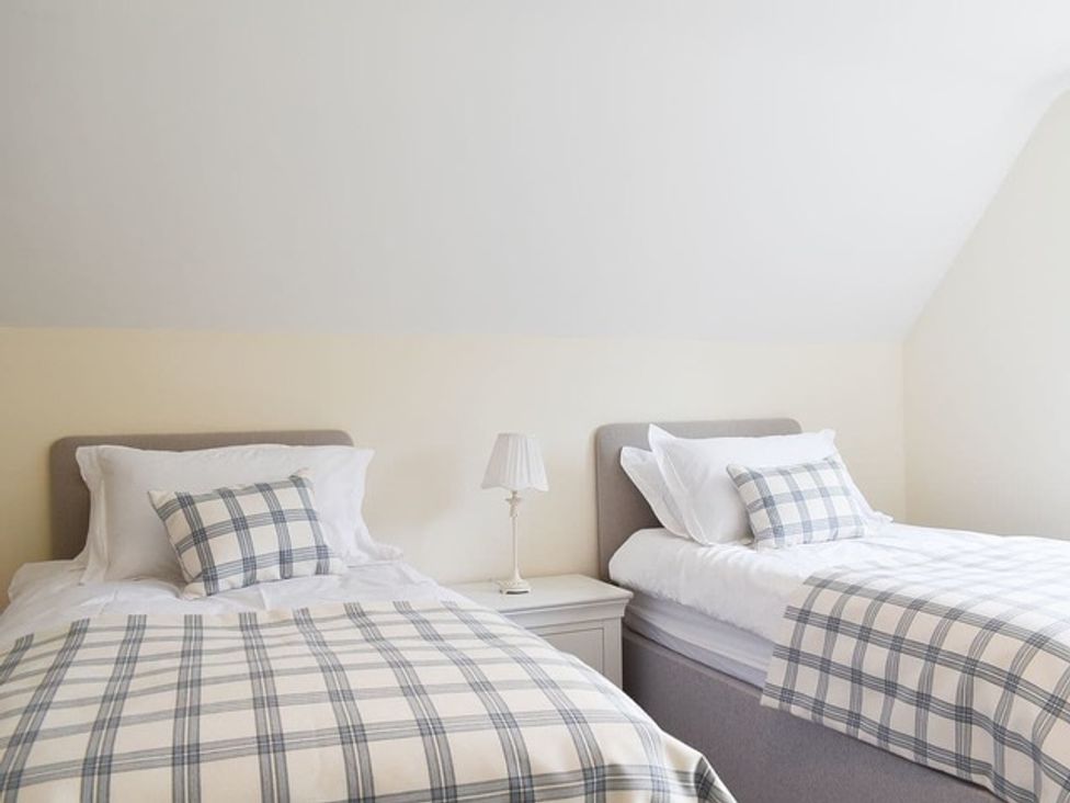 A bedroom with two beds and a lamp at Cae Coch Brynteg near Benllech