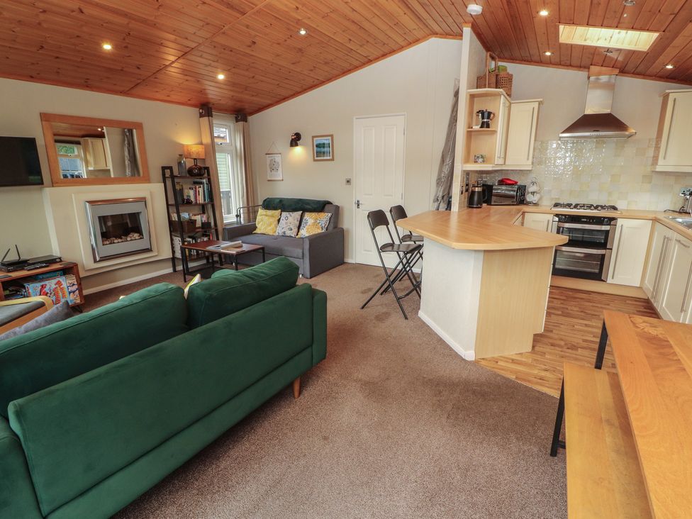 A living room with a sofa, television, and kitchen area at 28 Troutbeck in Bassenthwaite