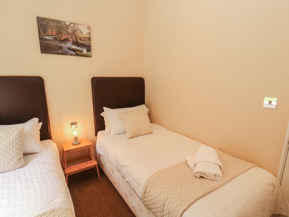A bedroom with two beds and a lamp at 28 Troutbeck in Bassenthwaite