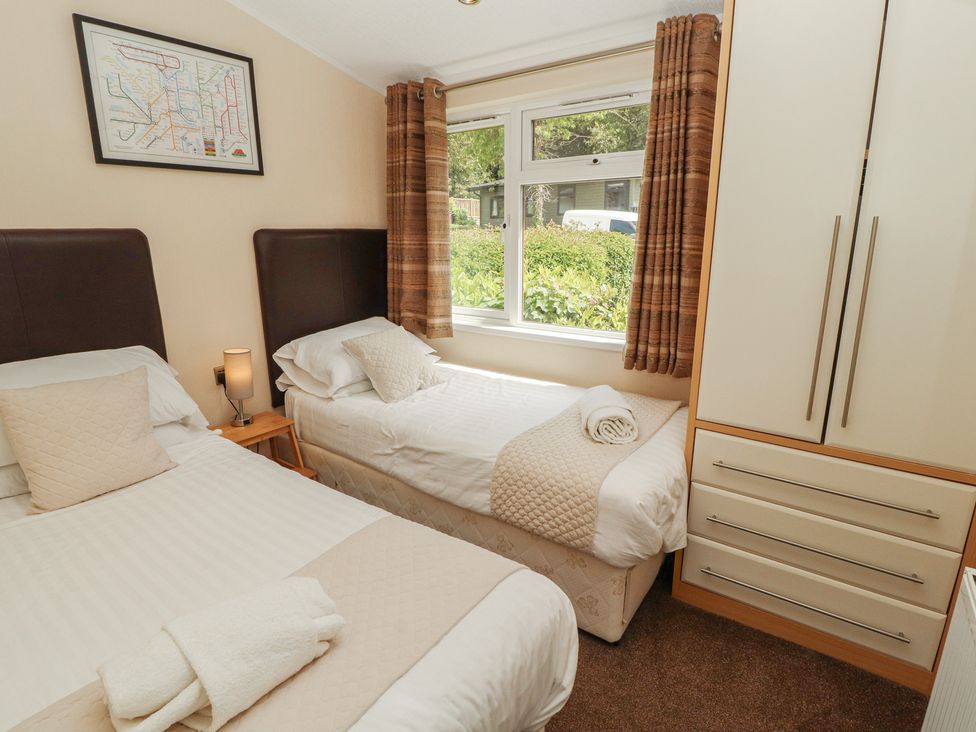 A bedroom with two beds and a wardrobe at 28 Troutbeck in Bassenthwaite