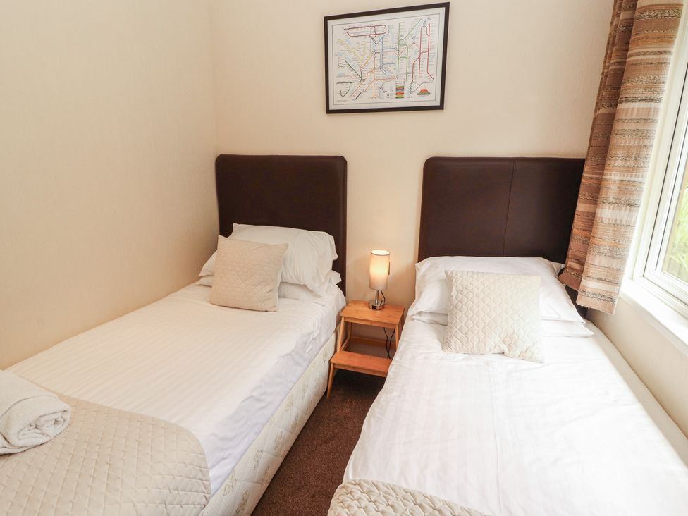 A bedroom with two single beds and a lamp at 28 Troutbeck in Bassenthwaite