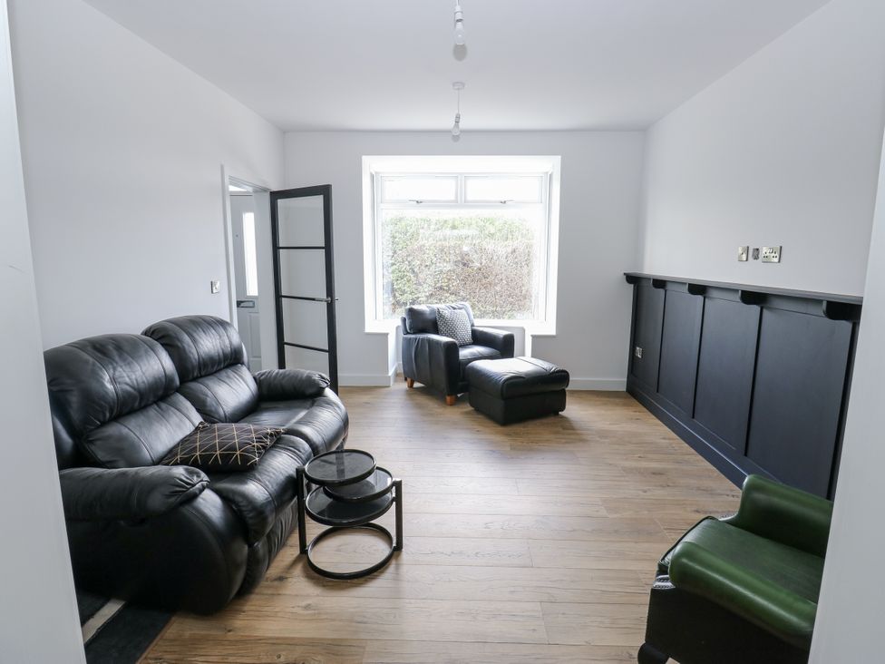 A living room with a black sofa and armchair at 489 New Hey Road in Huddersfield