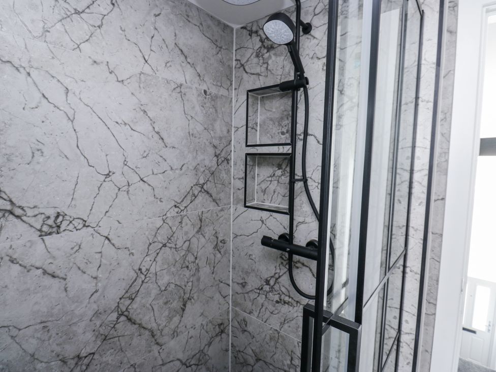 A shower with marble tiles and a showerhead at 489 New Hey Road in Huddersfield