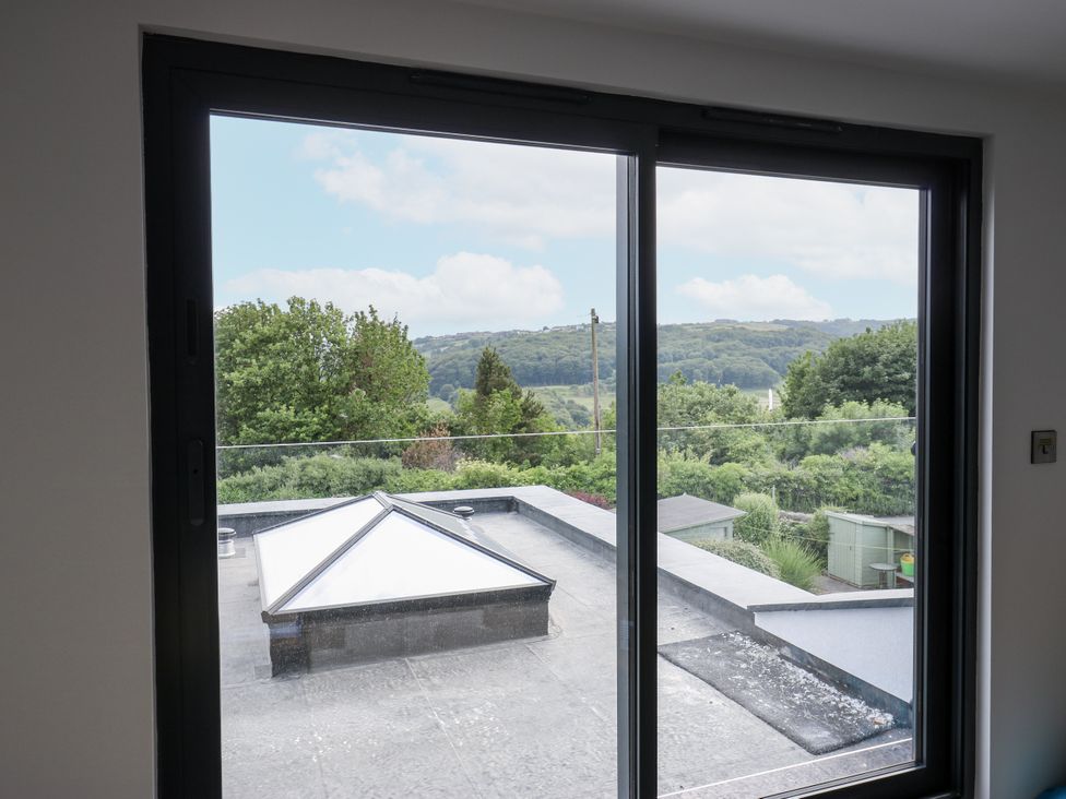 A view from a window showing a rooftop and trees at 489 New Hey Road Huddersfield
