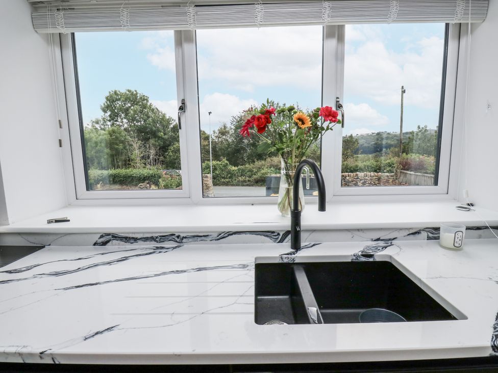 A kitchen with a sink and flowers on the countertop at Ellis House in Huddersfield