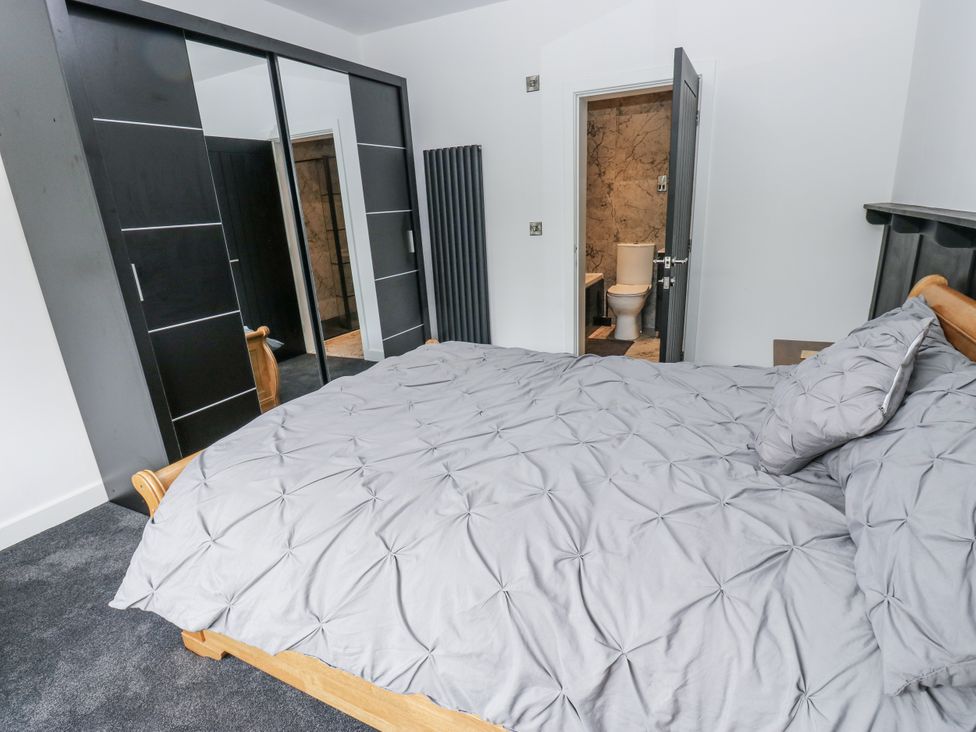 A bedroom with a bed and wardrobe visible at Ellis House in Huddersfield