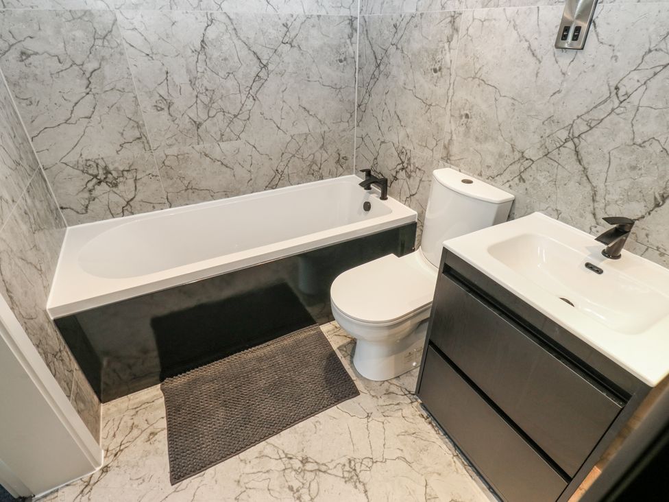 A bathroom with a bathtub, toilet, and sink at Ellis House in Huddersfield