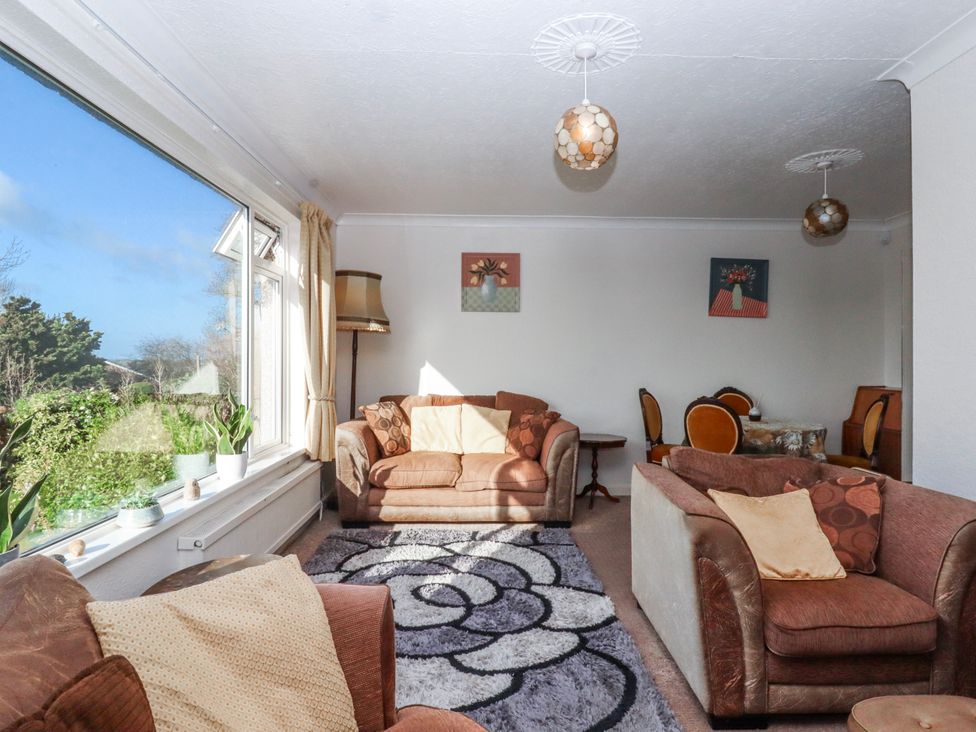 A living room with sofas, a coffee table, and a lamp at 7 Erme Drive in Ivybridge