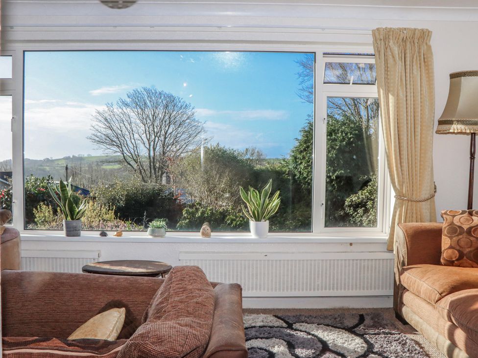 A living room with a large window and plants at 7 Erme Drive in Ivybridge