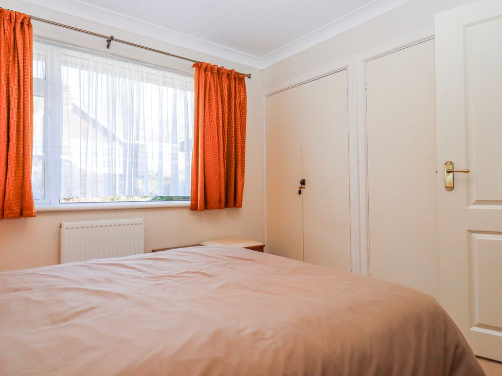 A bedroom with orange curtains and a bed at 7 Erme Drive Ivybridge