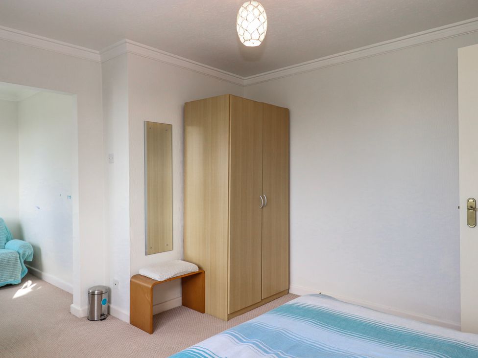 A bedroom with a bed, wardrobe, and stool at 7 Erme Drive in Ivybridge