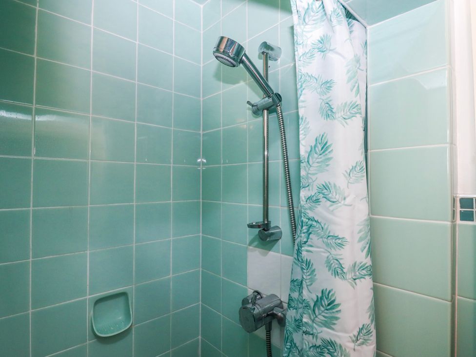 A shower with a curtain and tiled walls at 7 Erme Drive in Ivybridge