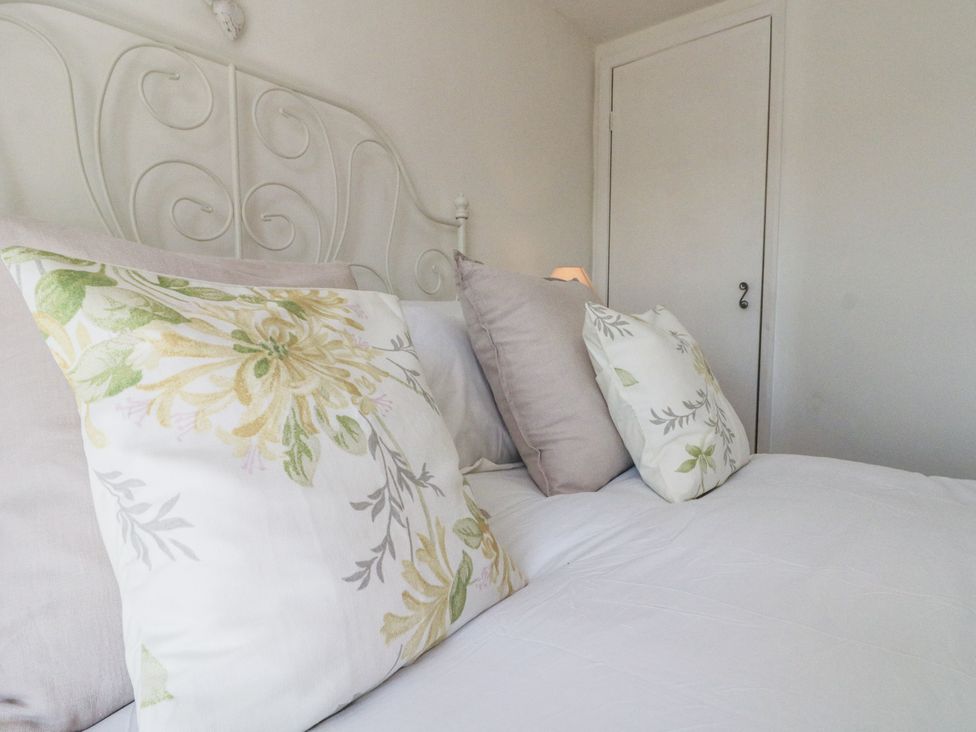 A bed with pillows and a bedside lamp at Honeysuckle Cottage in York