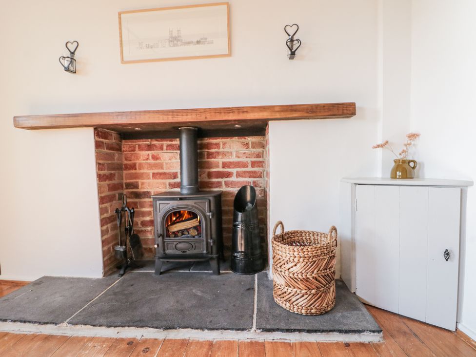 A living room with a wood stove and basket at Honeysuckle Cottage Oswaldkirk near Helmsley