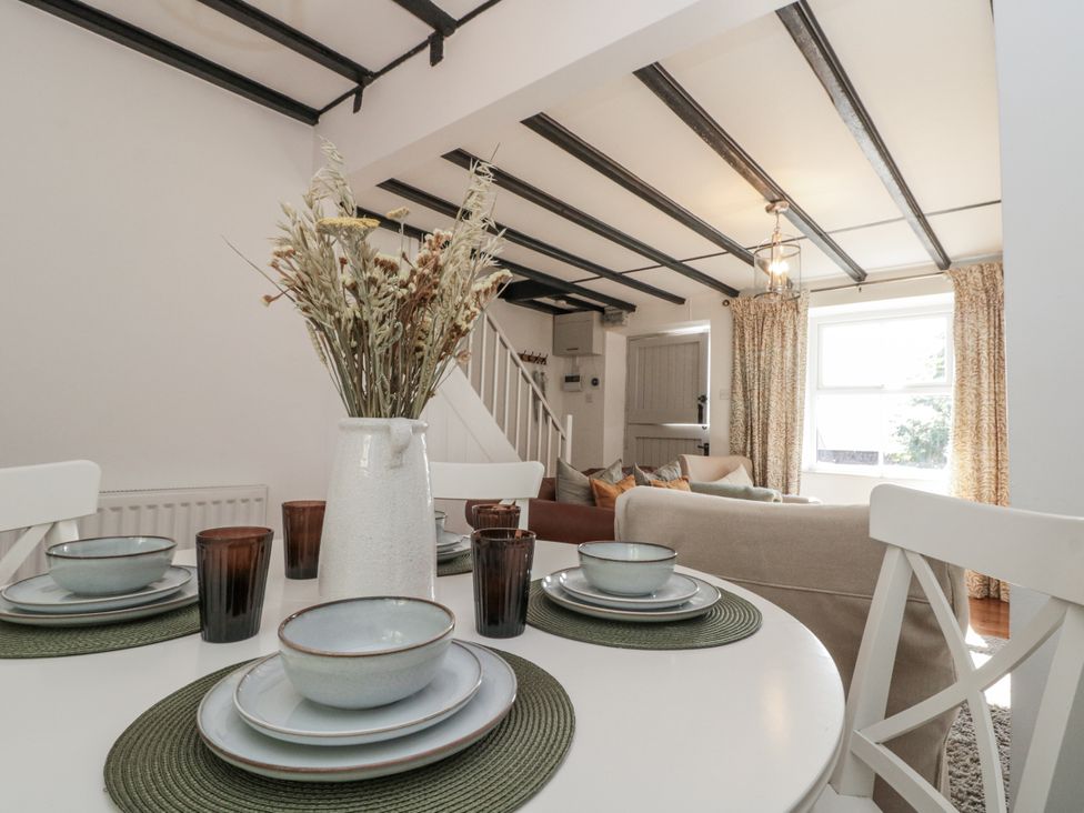 A dining table with dishes and a vase in Honeysuckle Cottage Oswaldkirk near Helmsley
