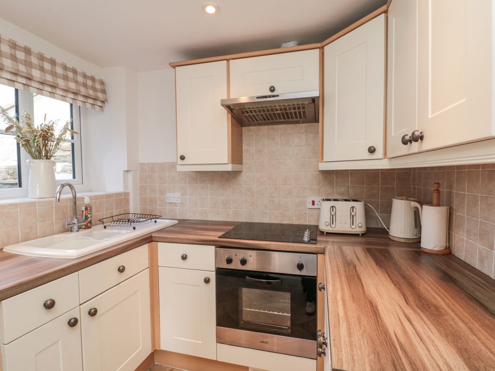A kitchen with a sink, stove, oven, toaster, and kettle at Honeysuckle Cottage in Oswaldkirk near Helmsley