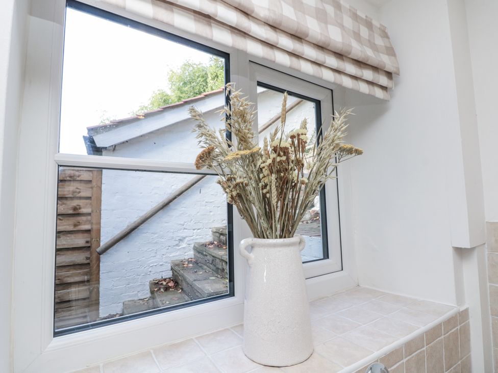 A window with a flower vase on the windowsill at Honeysuckle Cottage in Oswaldkirk near Helmsley