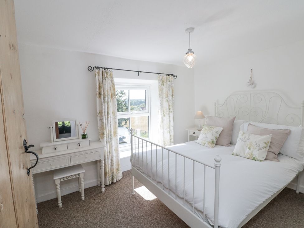 A bedroom with a bed, dresser, and window at Honeysuckle Cottage Oswaldkirk near Helmsley