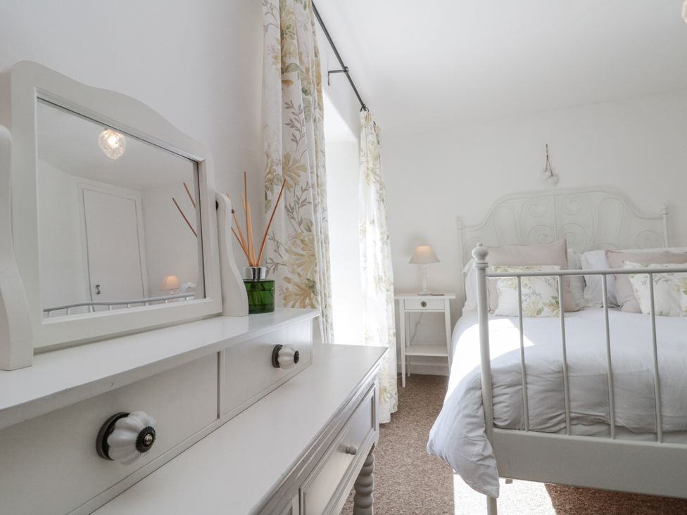 A bedroom with a bed and dresser at Honeysuckle Cottage near Helmsley