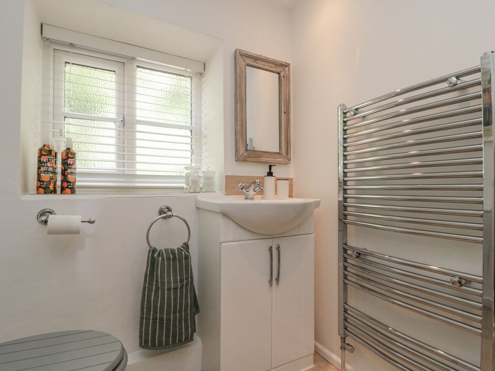 A bathroom with a sink, toilet, and heated towel rack at Honeysuckle Cottage Oswaldkirk near Helmsley