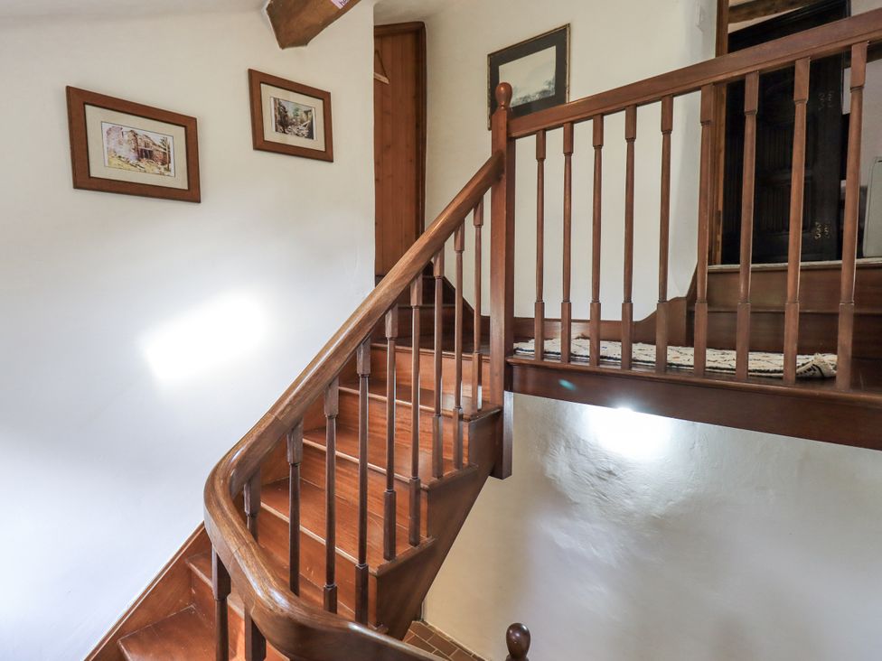 A staircase with wooden handrail and paintings at Chapel Cottage Ennerdale near Cleator Moor