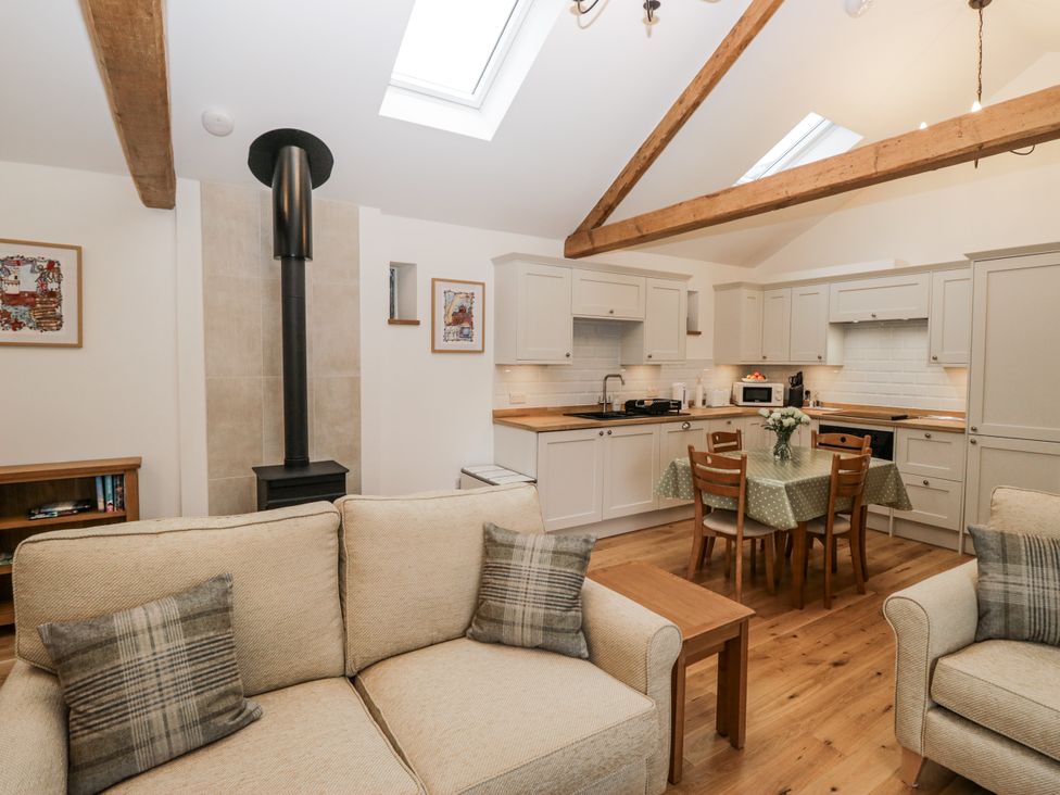 A living room with a kitchen area and seating at Swift Barn in Wigton