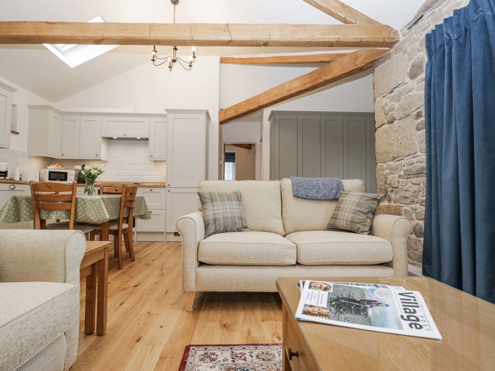 A living room with a sofa and dining area at Swift Barn, Wigton