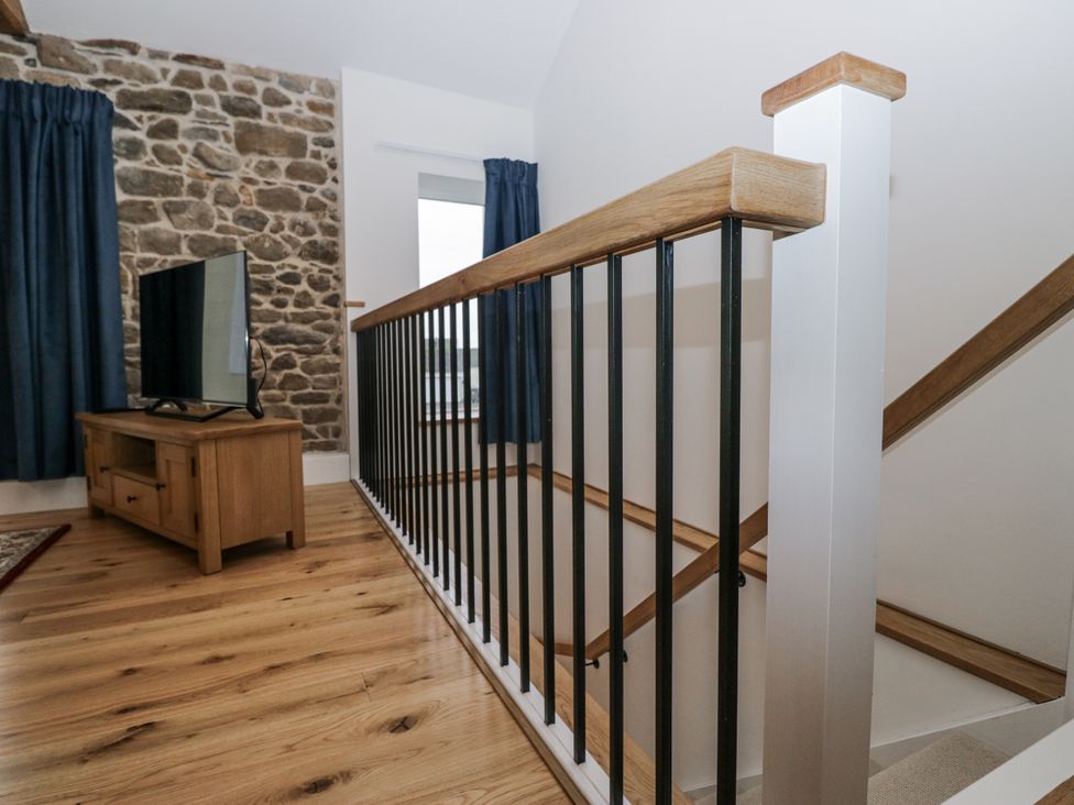 A stairway with a television and curtains at Swift Barn in Wigton