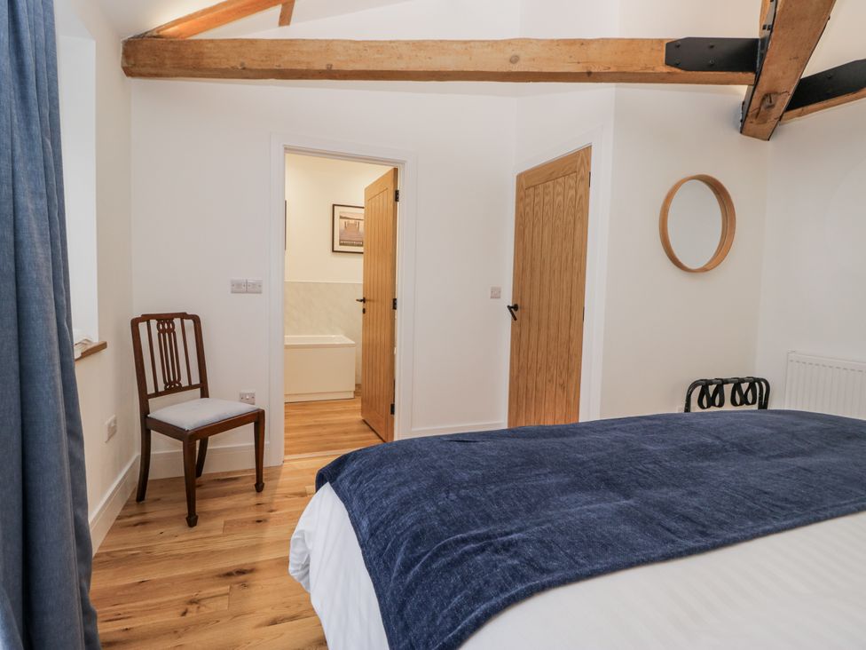 A bedroom with a bed and a chair at Swift Barn in Wigton