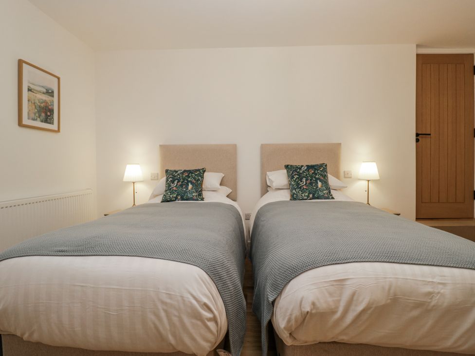 A bedroom with two single beds and wall art at Swift Barn in Wigton