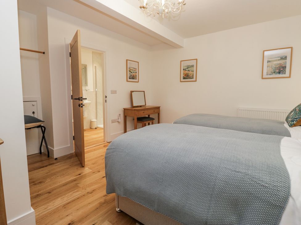 A bedroom with two beds and a table at Swift Barn in Wigton