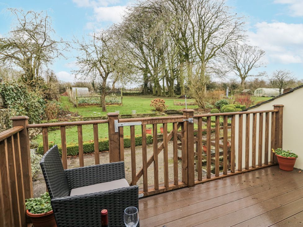 A garden view from a deck with furniture at Swift Barn in Wigton