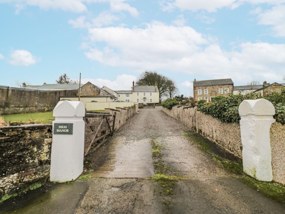 A driveway leading to buildings with a sign at High Manor in Wigton