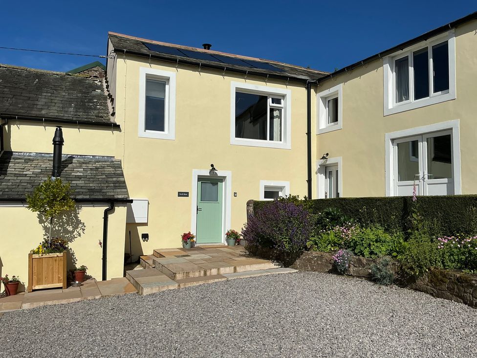 A house with a green door and steps at Swift Barn in Gilcrux