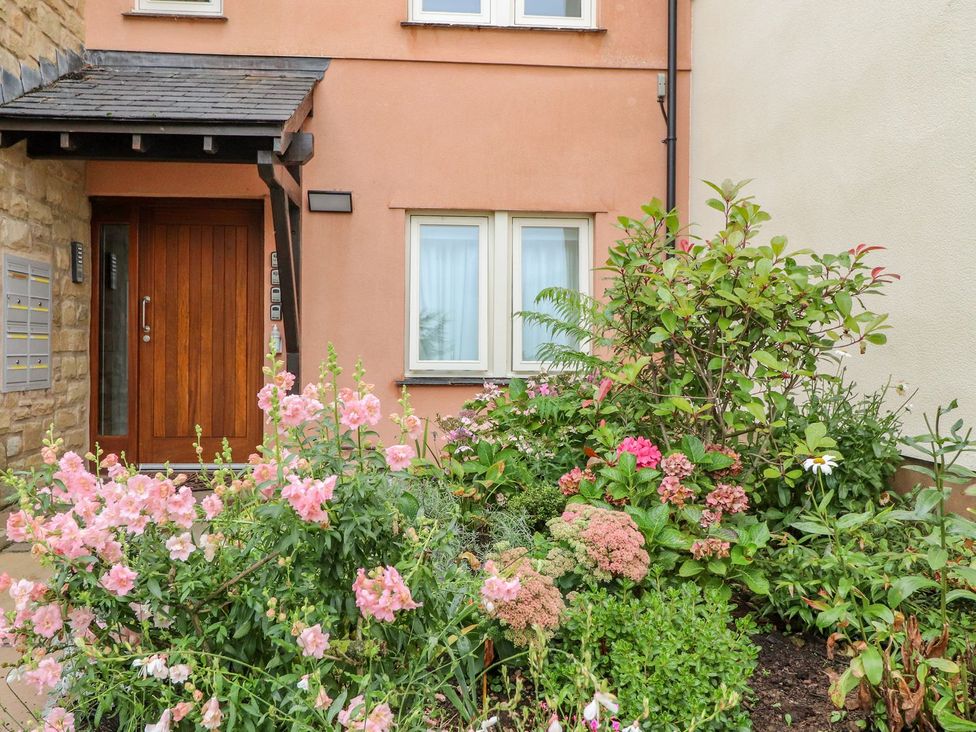 An entrance door with mailbox and intercom beside a window with garden plants and flowers outside at High View Meadows in Kirkby Lonsdale