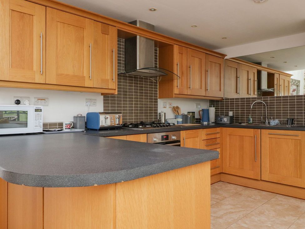 A kitchen with wooden cabinets black countertops and various appliances at High View Meadows in Kirkby Lonsdale