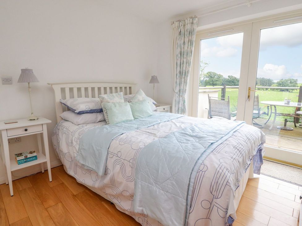 A bedroom with a bed and pillows next to glass doors leading to a deck at High View Meadows in Kirkby Lonsdale