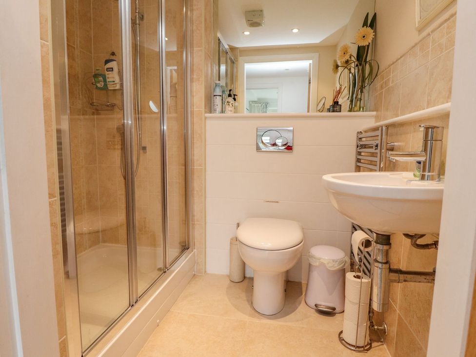 A bathroom with a shower enclosure toilet sink and decorative flowers at High View Meadows in Kirkby Lonsdale