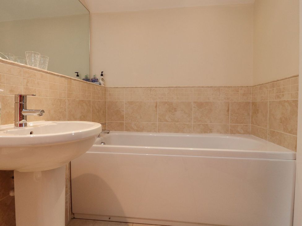 A bathroom with a white sink and a bathtub with beige tiled walls at High View Meadows in Kirkby Lonsdale