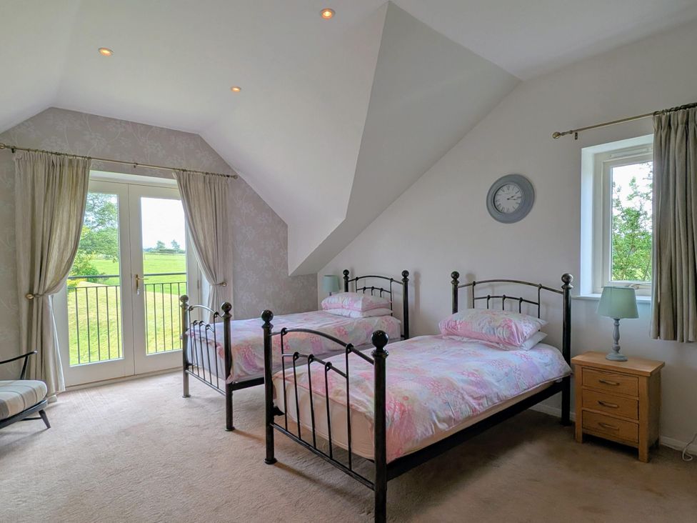 A bedroom with two beds and a nightstand at High View Meadows in Kirkby Lonsdale