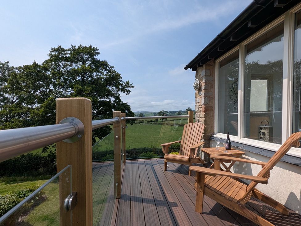 A balcony with wooden chairs and a table at High View Meadows in Kirkby Lonsdale
