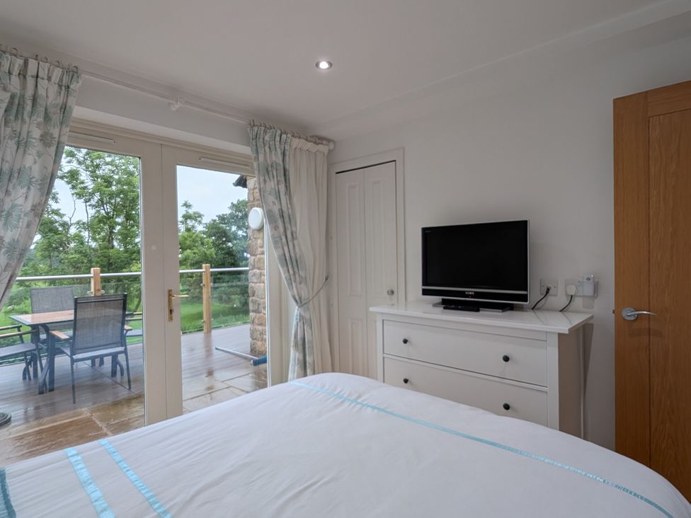 A bedroom with a television and a door leading to a deck at High View Meadows in Kirkby Lonsdale