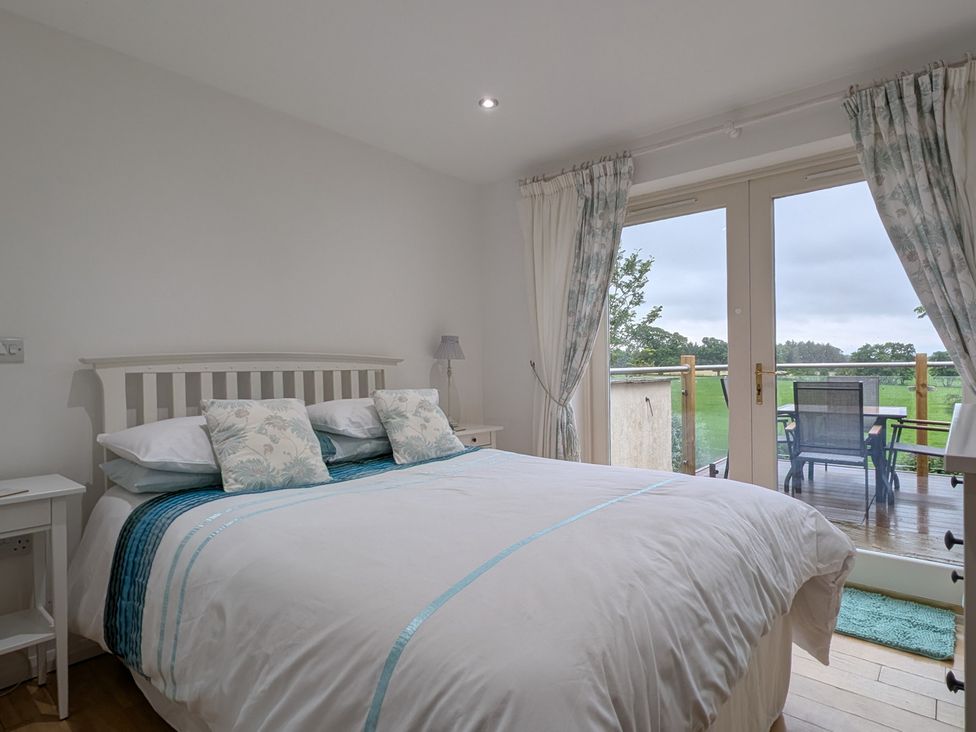 A bedroom with a bed and balcony access at High View Meadows in Kirkby Lonsdale