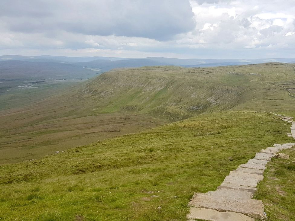 A landscape with a stone path leading through hills at High View Meadows in Kirkby Lonsdale