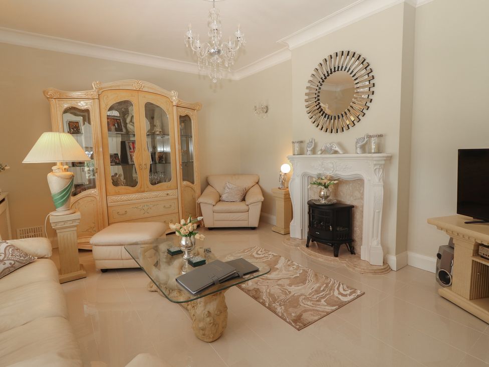 A living room with a glass coffee table a beige sofa a cabinet and a fireplace at Killelton Cottage Camp County Kerry