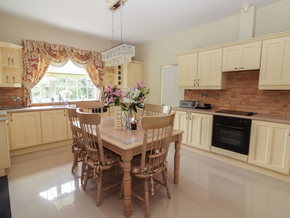 A kitchen with wooden dining table and chairs flowers on table and cream cabinets at Killelton Cottage Camp County Kerry