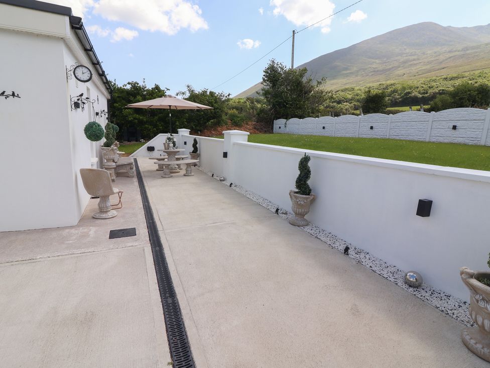 An outdoor patio area with stone tables and benches umbrellas and potted plants at Killelton Cottage in Camp County Kerry