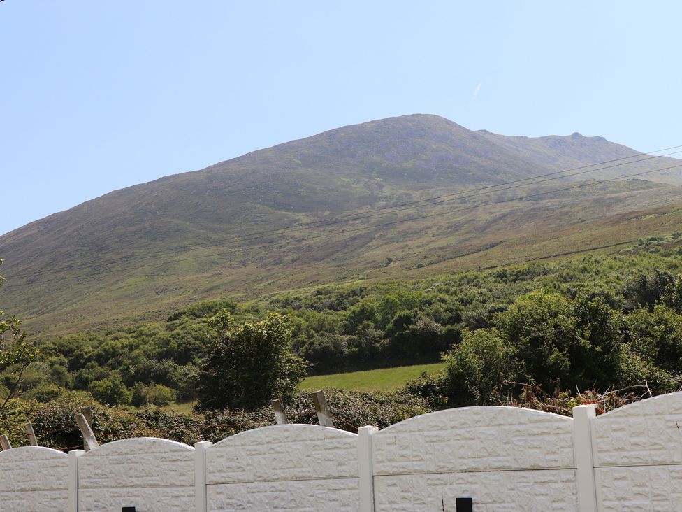 A mountain with green vegetation behind a white fence in a rural area